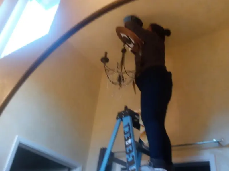 Electrician installing a chandelier in a Waggaman residence